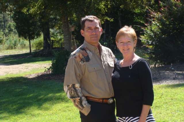 A man and woman standing in a grassy area.