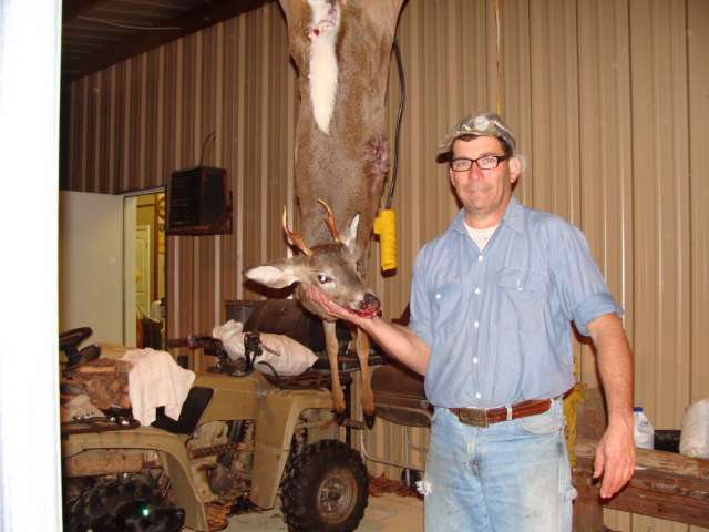 A man holding a deer in a garage.