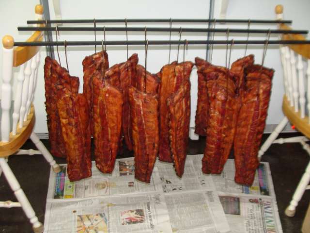 Bacon hanging on a rack in a kitchen.