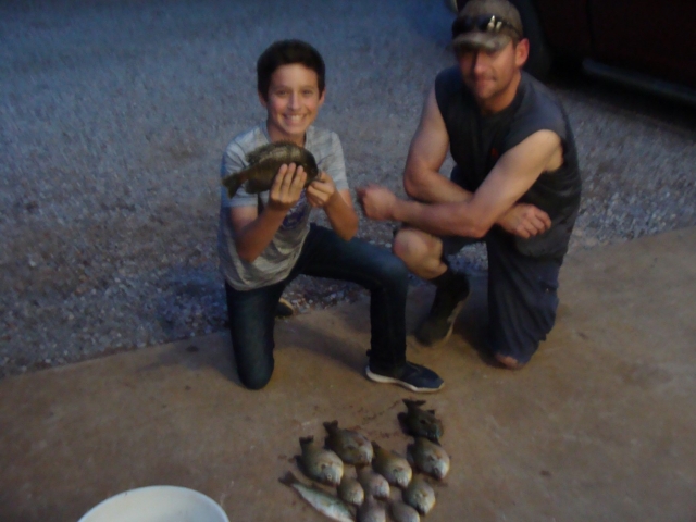 A man and a boy posing for a picture with some fish.