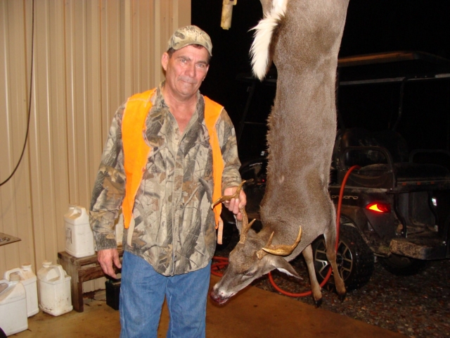A man standing next to a deer that has been shot.