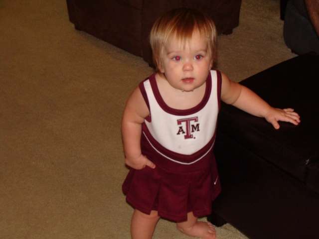 A young girl in a maroon and white cheerleader dress.