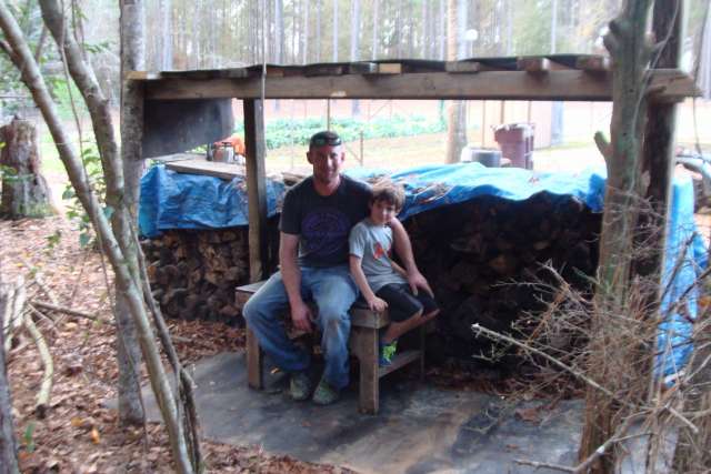 A man and a child sitting on a bench in the woods.