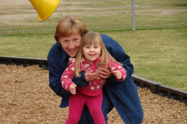 A woman holding a little girl on a playground.