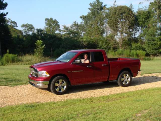 A red ram truck is parked on a gravel road.