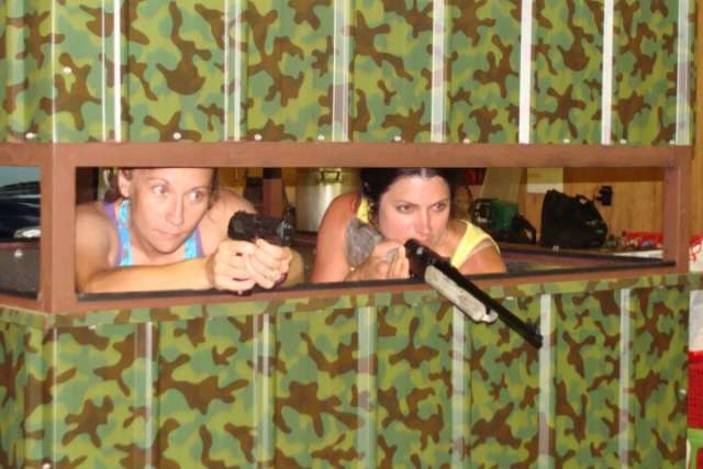 Two women in a camouflage room with guns.