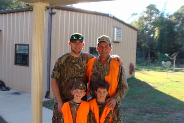 Three men in camouflage vests posing for a photo.