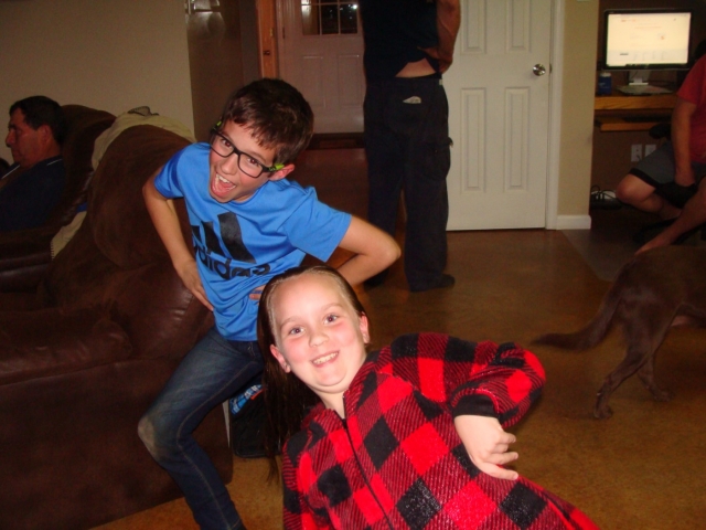 A boy and a girl posing for a picture in a living room.