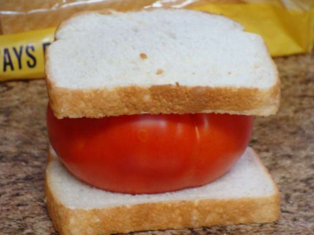 A sandwich with a tomato in the middle.