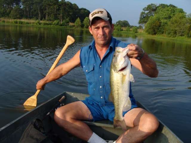 A man sitting in a canoe holding a large bass.